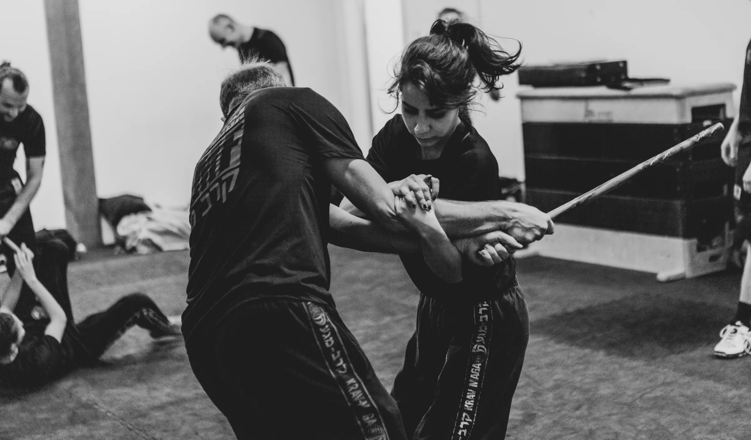 Frau wehrt im Training einen Stockangriff mit einer Hebeltechnik ab